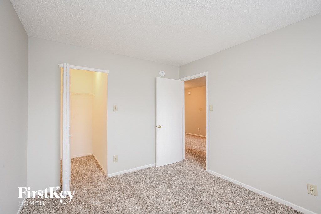 a bedroom with white walls and a doorway to a closet
