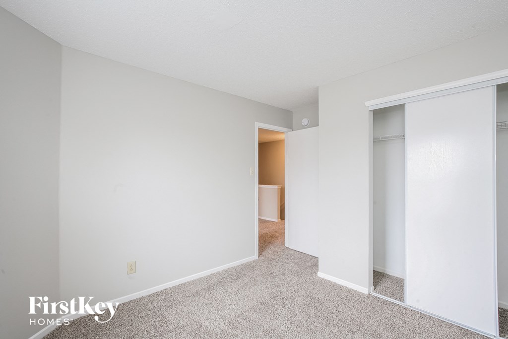 a bedroom with white walls and a door to a closet