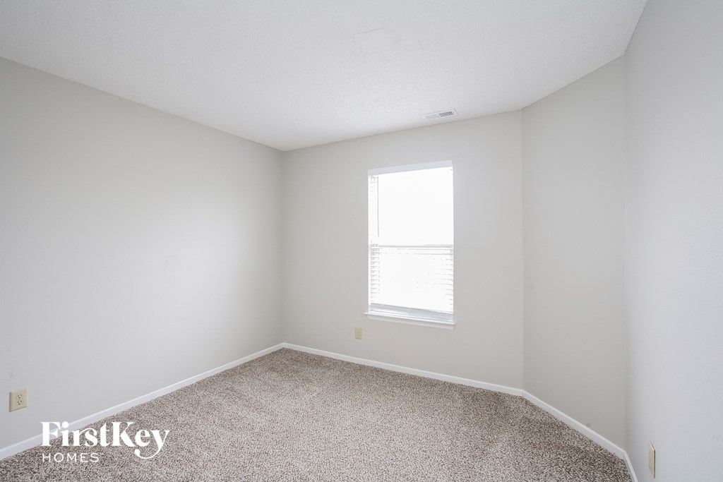 a bedroom with white walls and carpet and a window