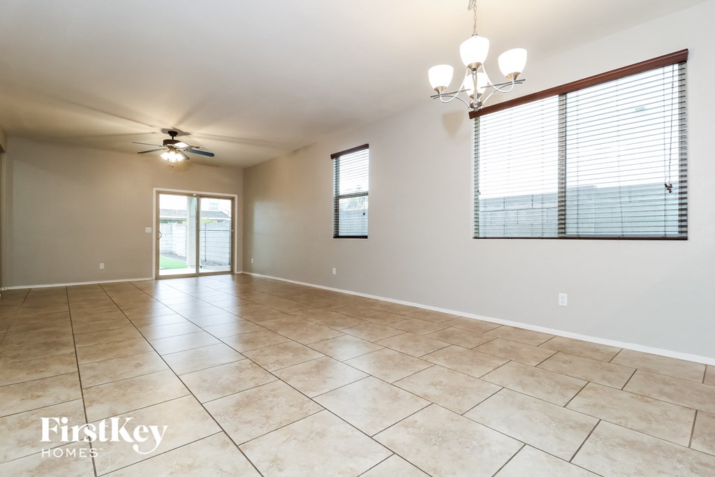 A spacious room with tile flooring and a ceiling fan.