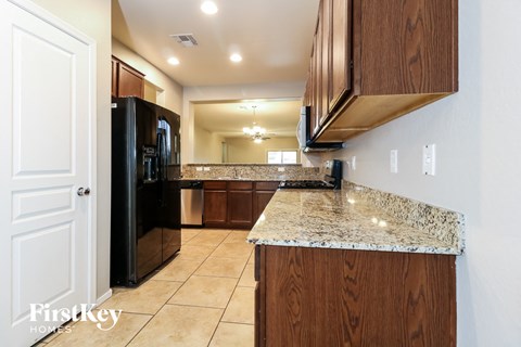A kitchen with a granite countertop and wooden cabinets.