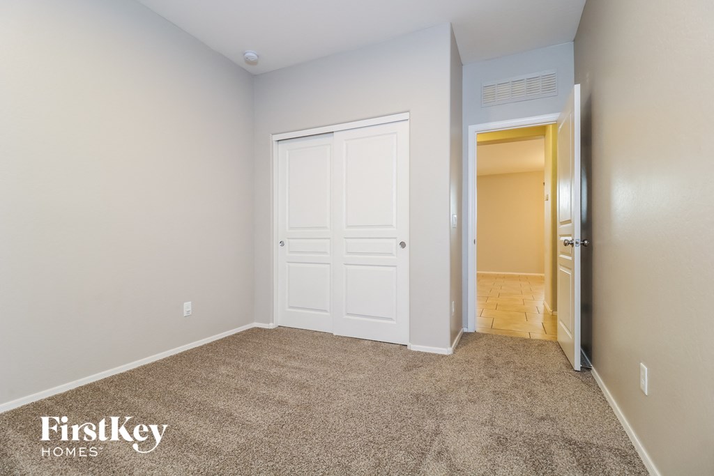 A bedroom with a white door and a carpeted floor.