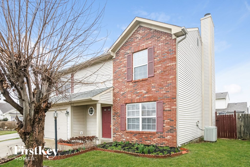 a small brick house with a tree in the yard
