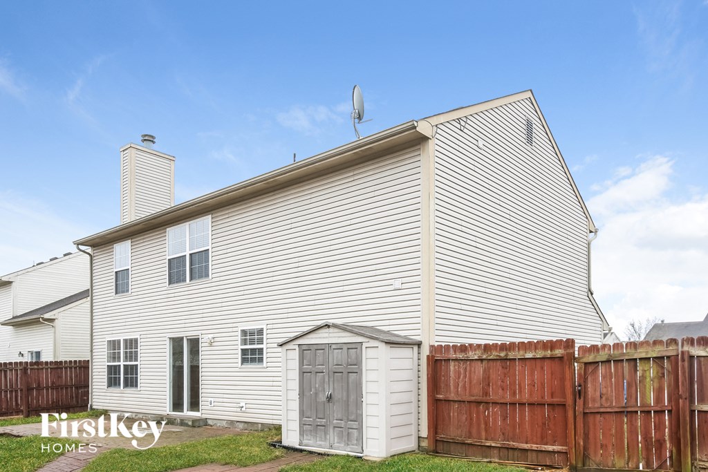 the outside of a white house with a wooden fence