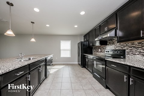A kitchen with black cabinets and a granite countertop.