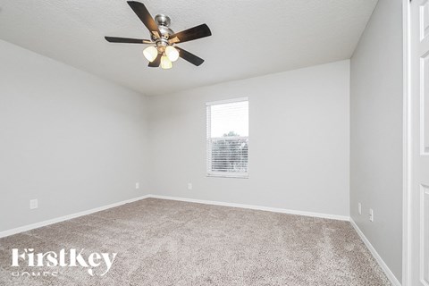 the spacious living room with ceiling fan and carpet