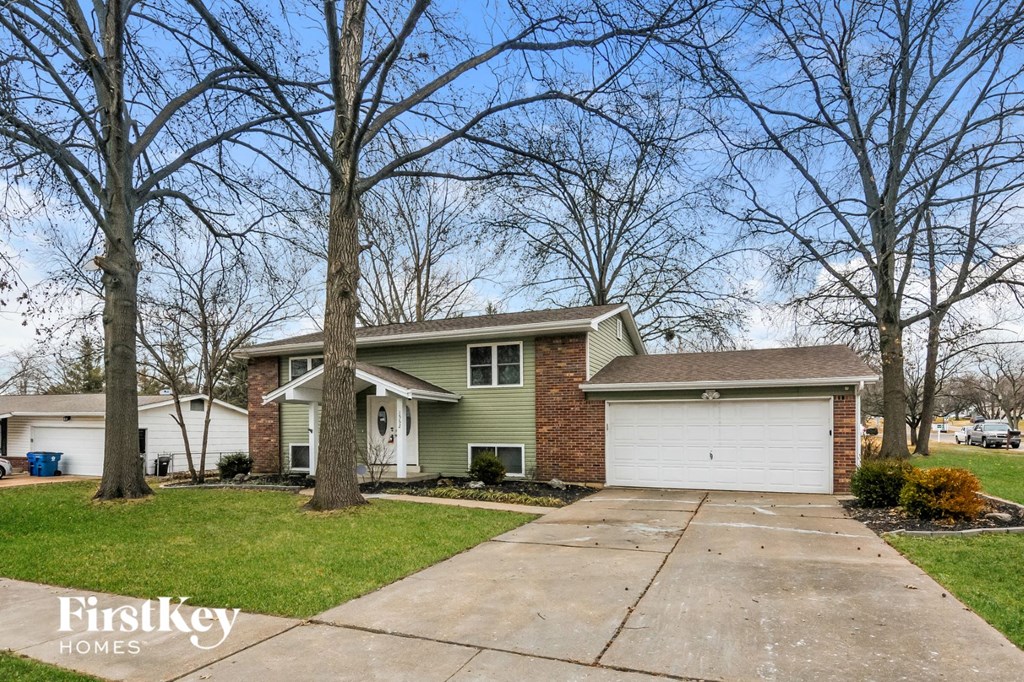A house with a garage is surrounded by bare trees.