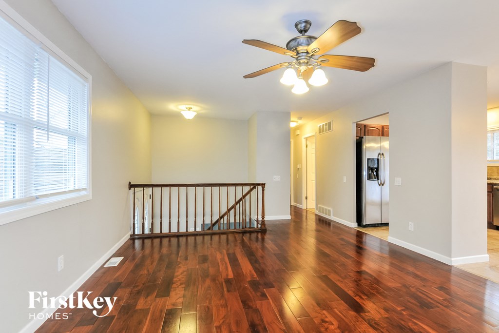 A spacious room with a wooden floor and a ceiling fan.