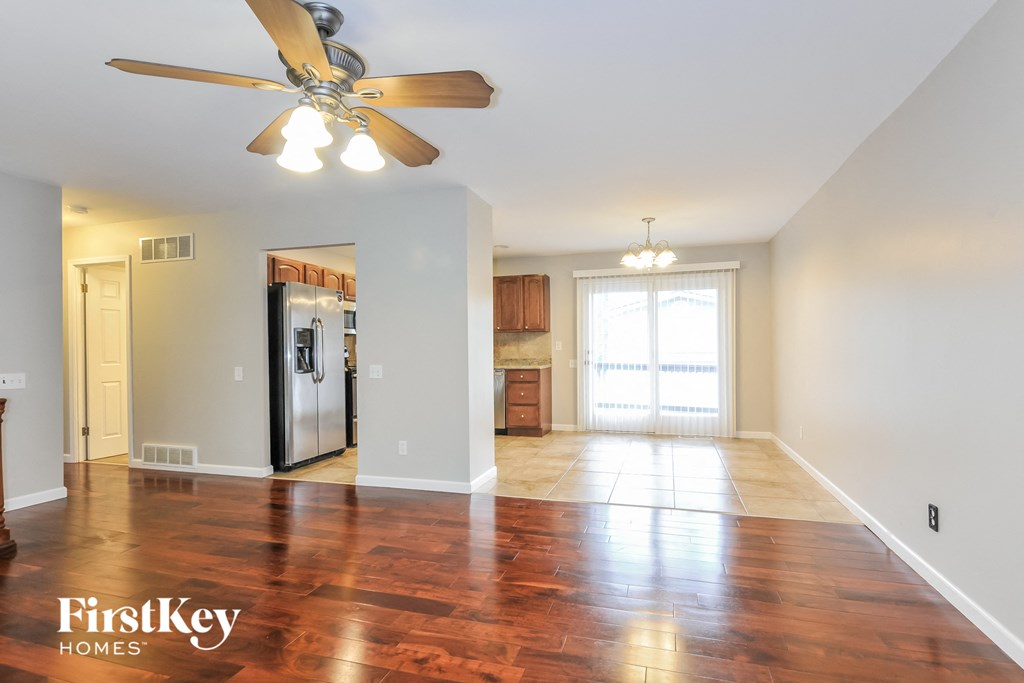 A spacious room with a wood floor and a ceiling fan.