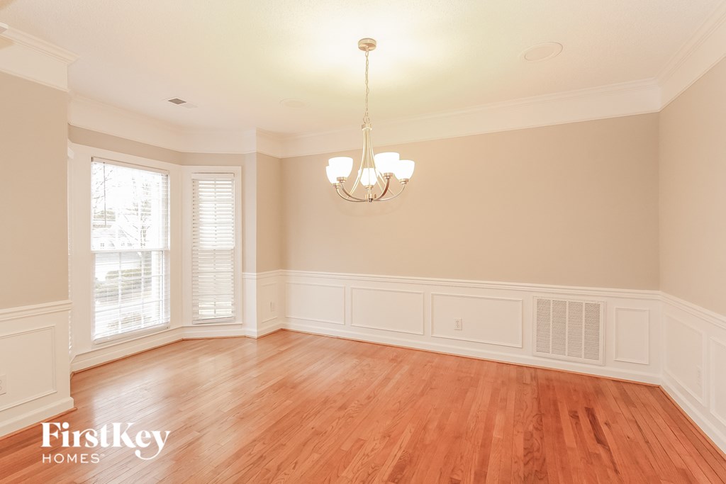 an empty dining room with wood floors and a chandelier