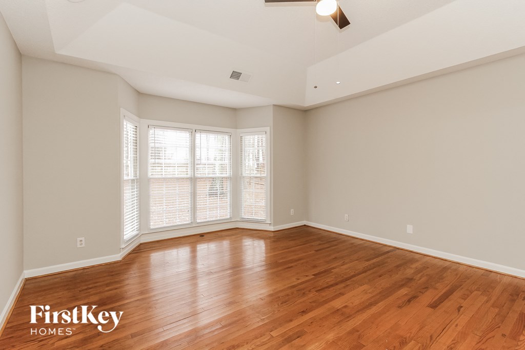 an empty living room with wood floors and large windows