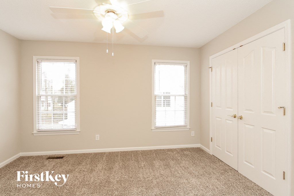 a empty bedroom with a ceiling fan and two windows