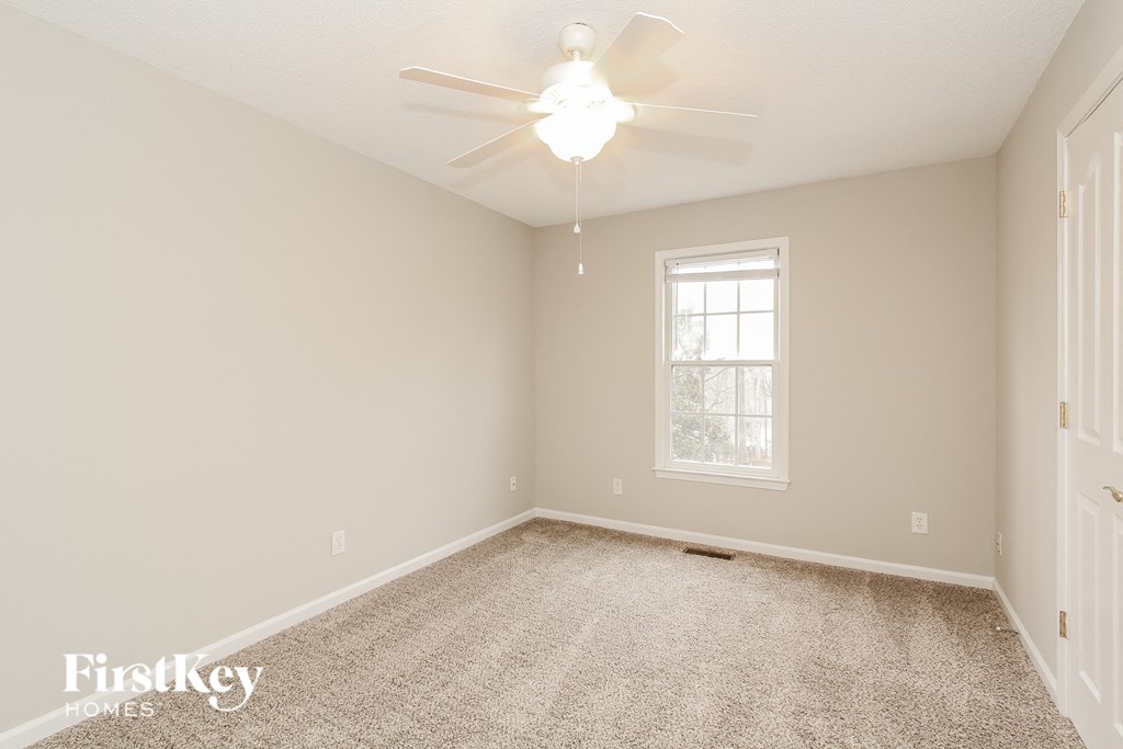 a empty room with a ceiling fan and a window