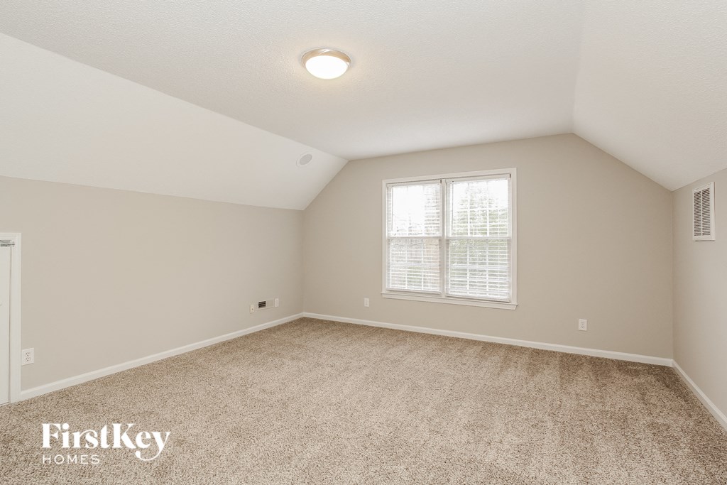 a spacious bedroom with carpeting and a window