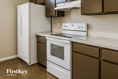 A white refrigerator is in a kitchen with a stove and oven.