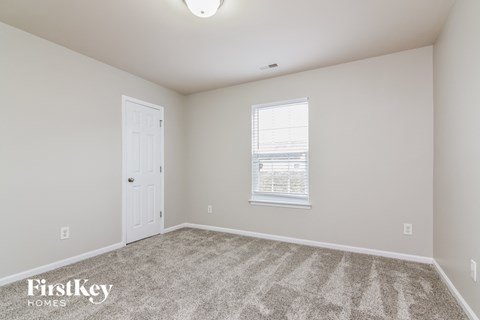 a bedroom with carpet and a door and a window