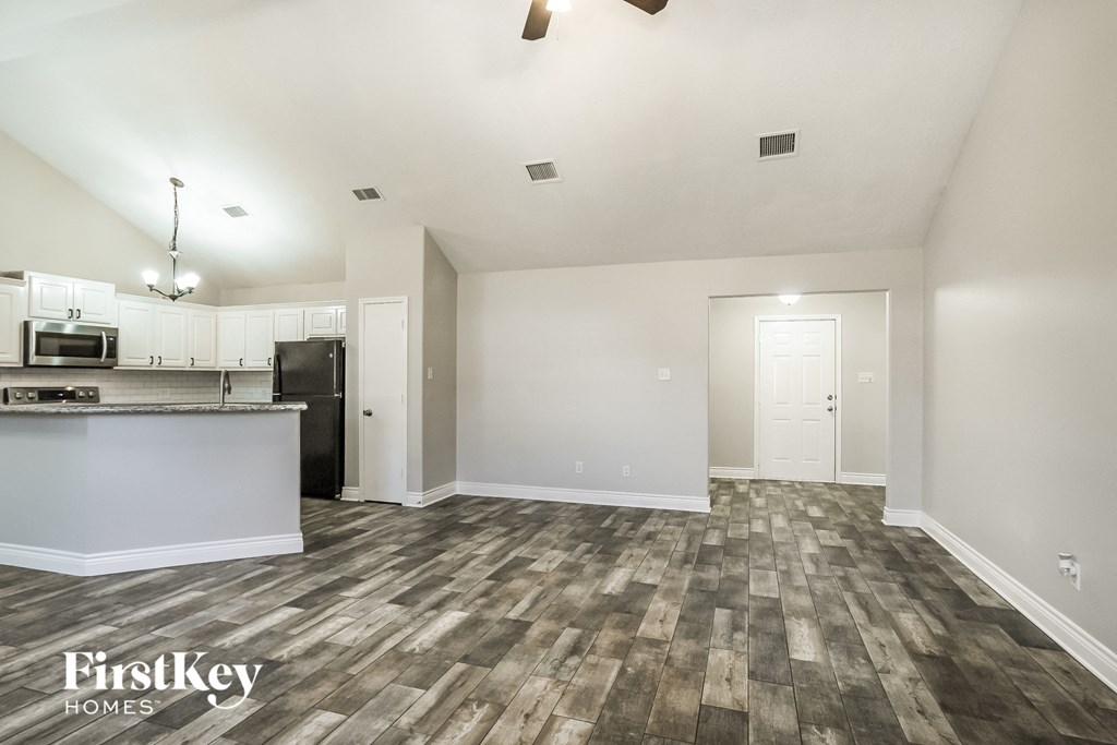A spacious room with a kitchen area and a bar.
