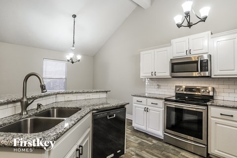A kitchen with a black dishwasher and stove top oven.