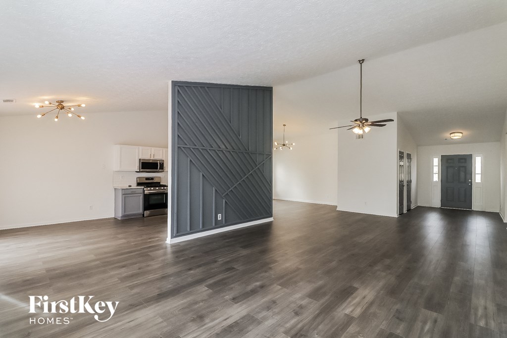 a sliding barn door in an empty living room with a kitchen in the background