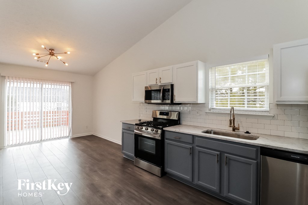 a kitchen with blue cabinets and white appliances and a sliding glass door