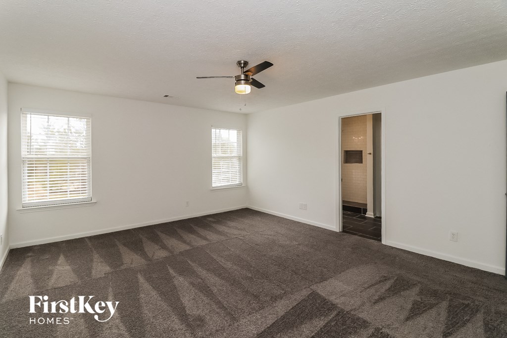 a living room with carpet and a ceiling fan