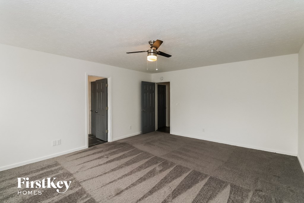 an empty living room with a ceiling fan and white walls