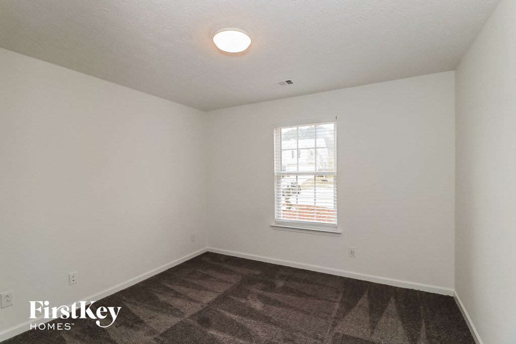 a bedroom with white walls and a window