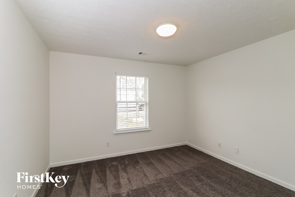 a bedroom with white walls and wood flooring and a window