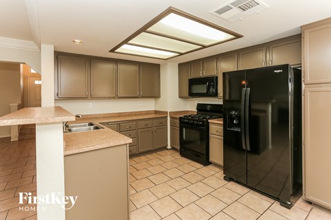 A kitchen with a black refrigerator, microwave, and oven.