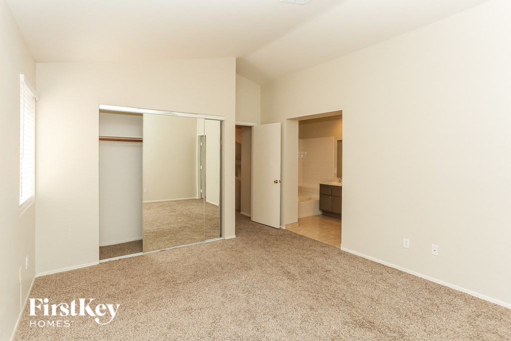 A bedroom with a mirrored closet door and a carpeted floor.