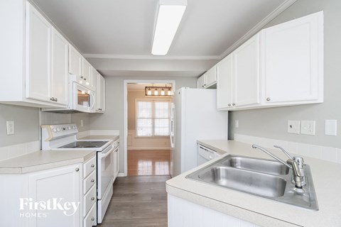 A kitchen with white cabinets and a stainless steel sink.
