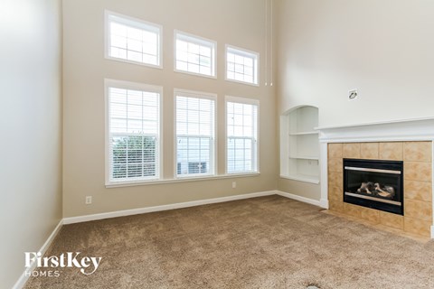 a living room with a fireplace and three windows