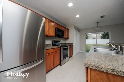 A kitchen with a stainless steel refrigerator and wooden cabinets.
