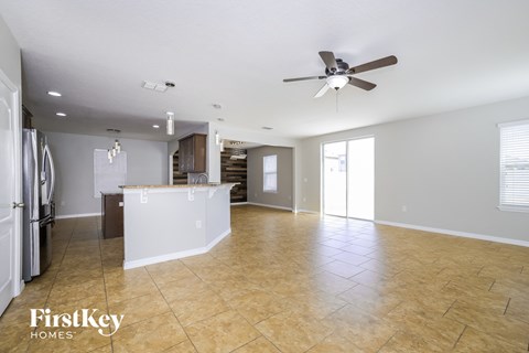 an empty kitchen and living room with a ceiling fan