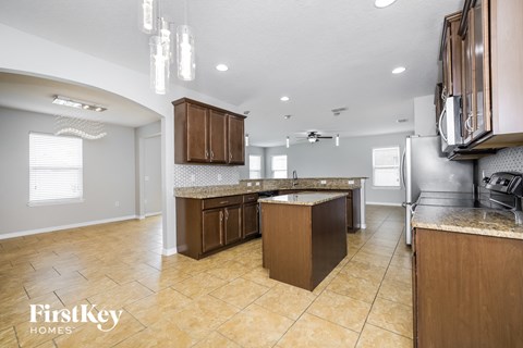 a kitchen with wooden cabinets and tile floors and a stainless steel refrigerator