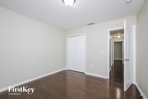 the living room of an apartment with wood floors and white walls