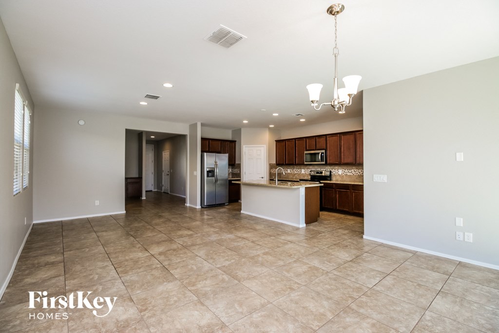 A spacious kitchen and living room with a chandelier and tiled flooring.