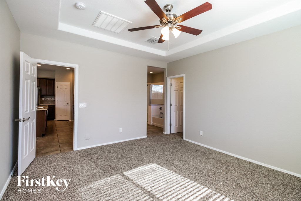 A spacious room with a ceiling fan and a rug on the floor.