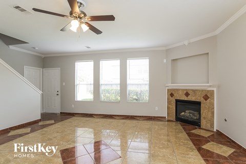 A spacious living room with a fireplace and a ceiling fan.