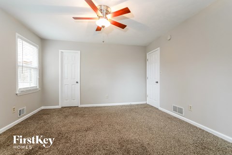 the spacious living room with ceiling fan and carpet