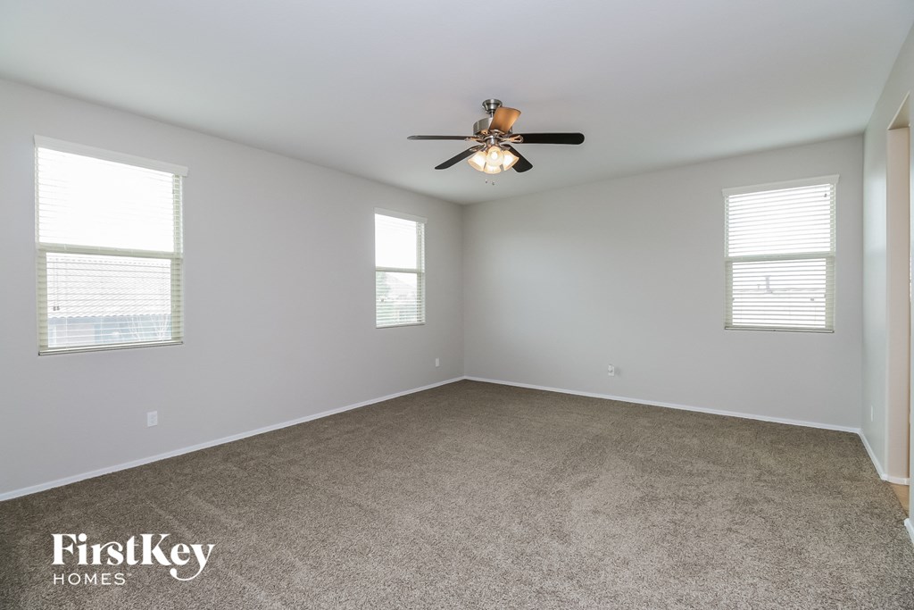 an empty room with a ceiling fan and two windows
