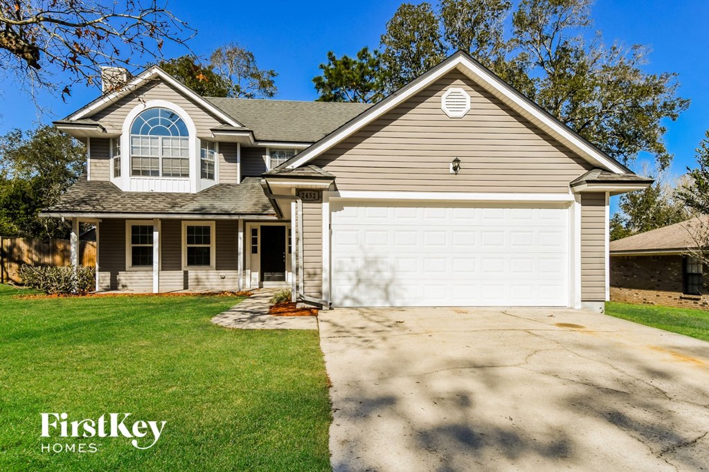 A house with a garage and a driveway in front of it.