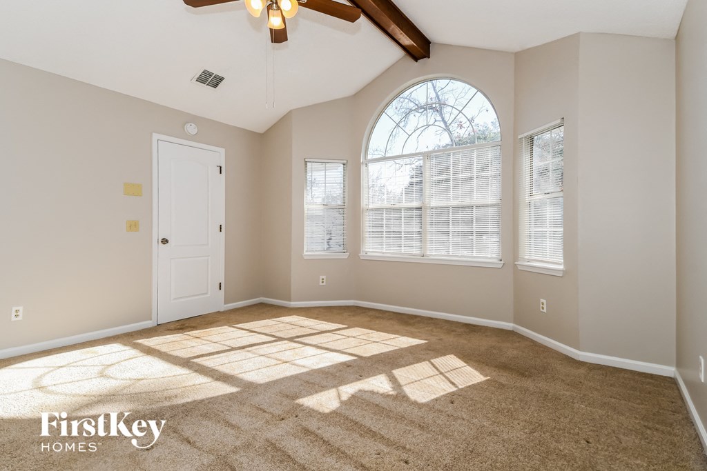 A spacious room with a carpeted floor and a ceiling fan.