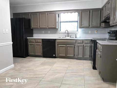 A kitchen with a black refrigerator and cabinets.