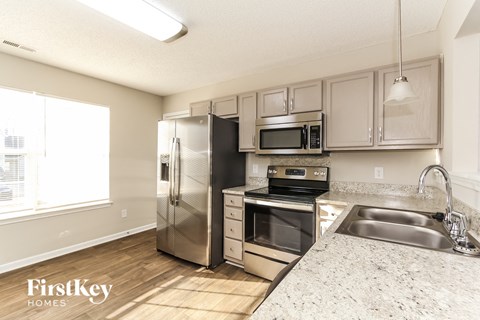 A kitchen with a stainless steel refrigerator, microwave, oven, and sink.