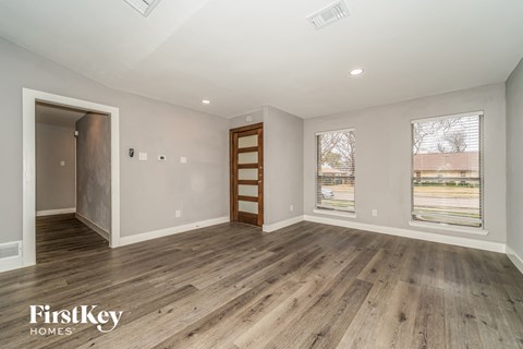 A spacious room with wooden flooring and a view of a highway outside the window.