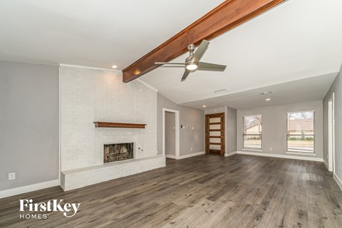 A spacious room with a fireplace and wooden floors.