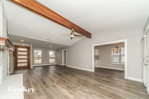 A spacious room with wooden floors and a large window.