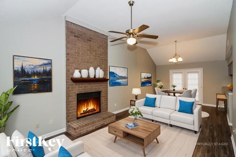 A living room with a fireplace and a painting of a lake scene on the wall.