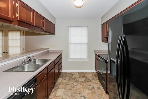 A kitchen with a black refrigerator and brown cabinets.